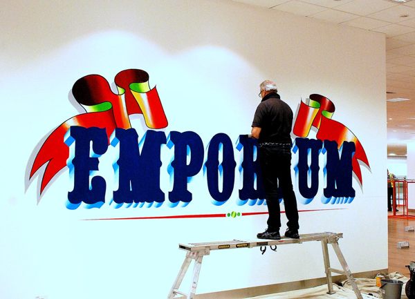 Ray Pedersen (PaintnSign) Hand Painting the Bespoke Myers MyKids Emporium Sign